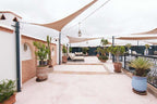 Outdoor terrace at The Central House Marrakech Medina with terracotta pots, green plants, beige sun sails, and lounge seating