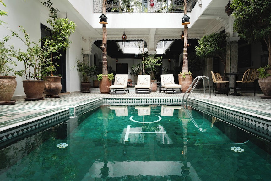 The Central House Marrakech Medina with a traditional Moroccan indoor pool featuring green mosaic tiles surrounded by potted plants and seating