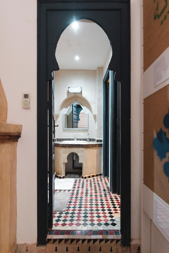Interior view through black arched doorway showing traditional Moroccan tiled floor in black, red, and white at The Central House Marrakech Medina