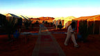 Tigmi Standard Desert Camp with white canvas tents and carpets lining sandy path in Moroccan desert under blue sky