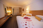 Timoulay Hotel & Spa Agadir spacious bedroom with wooden furniture, large bed adorned with rose petals, warm lighting, and a small sitting area