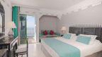 Hotel room at Timoulay Hotel & Spa Agadir with white and turquoise bedding, dark ornate wooden furniture, and balcony view