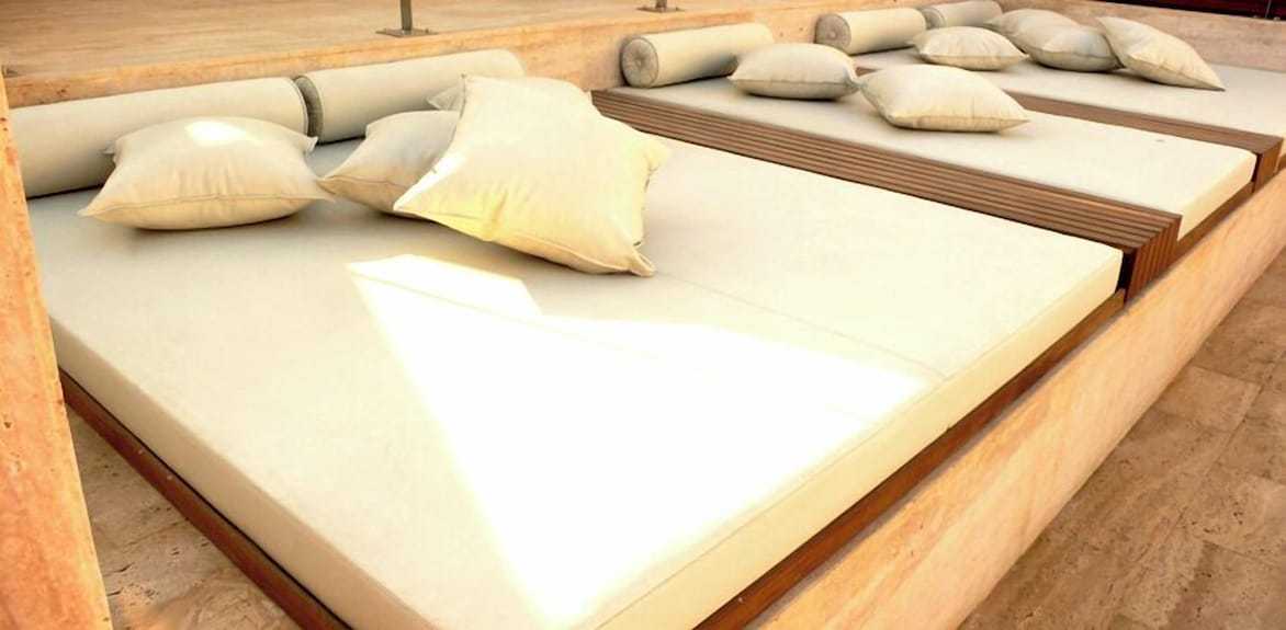 Outdoor beige cushioned lounge beds with multiple matching pillows at Timoulay Hotel & Spa Agadir outdoor relaxation area
