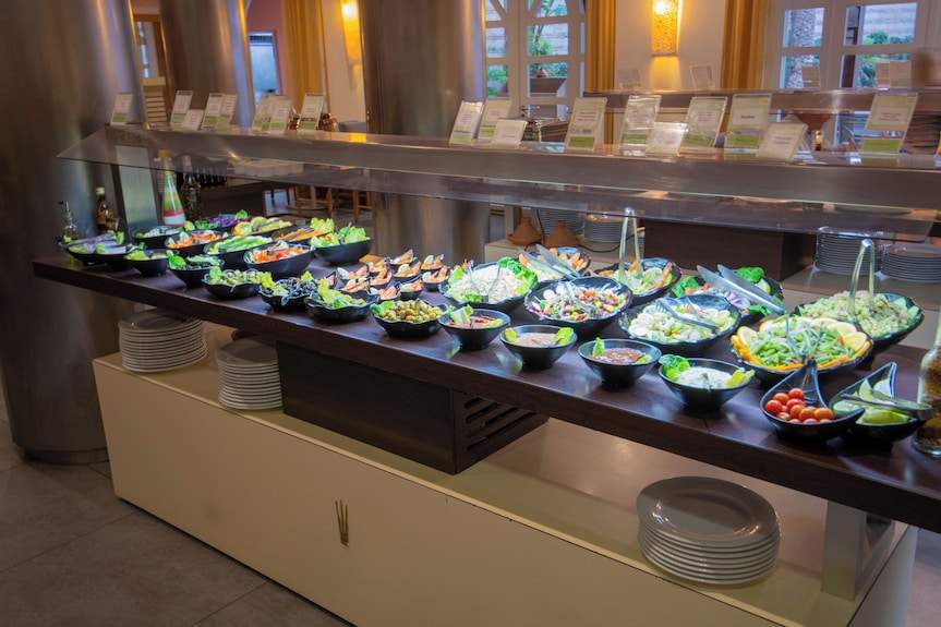 Buffet salad bar at Timoulay Hotel & Spa Agadir with assorted fresh vegetables and salads in black bowls on a dark wooden counter