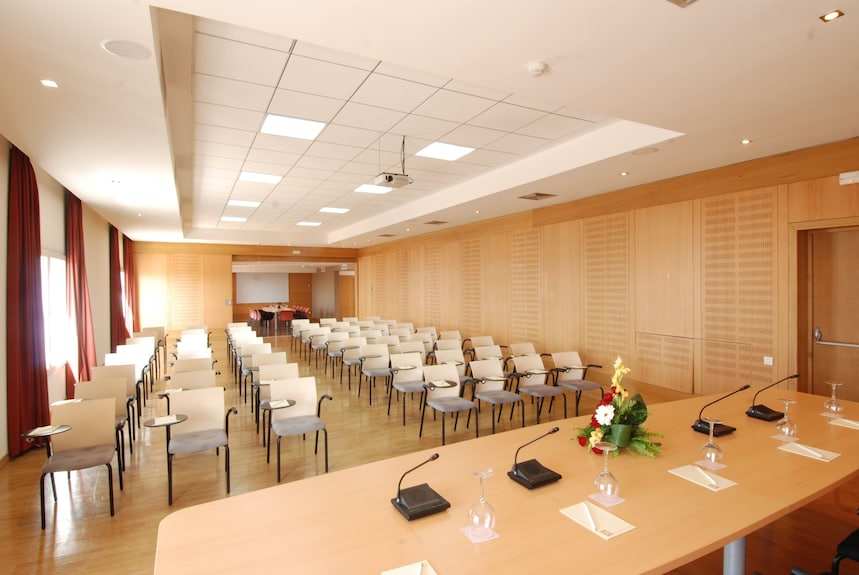 Conference room with multiple beige chairs, wooden panel walls, long table with microphones and flower centerpiece at Timoulay Hotel & Spa Agadir