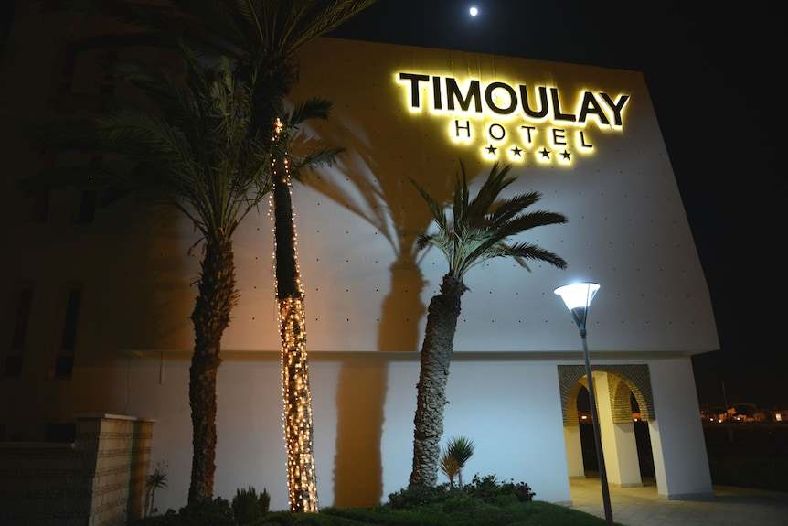 Exterior view of Timoulay Hotel & Spa Agadir at night with illuminated sign, palm trees, and warm lighting