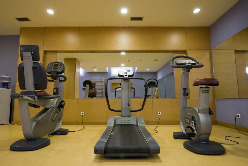 Fitness room at Timoulay Hotel & Spa Agadir featuring a treadmill, stationary bikes, and purple walls with large mirror