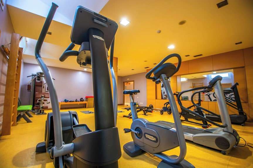 Timoulay Hotel & Spa Agadir gym with modern cardio equipment including stationary bike and elliptical machine in yellow-toned room