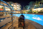 Timoulay Hotel & Spa Agadir illuminated outdoor pool area at night with Moroccan-style lantern and modern metal railing
