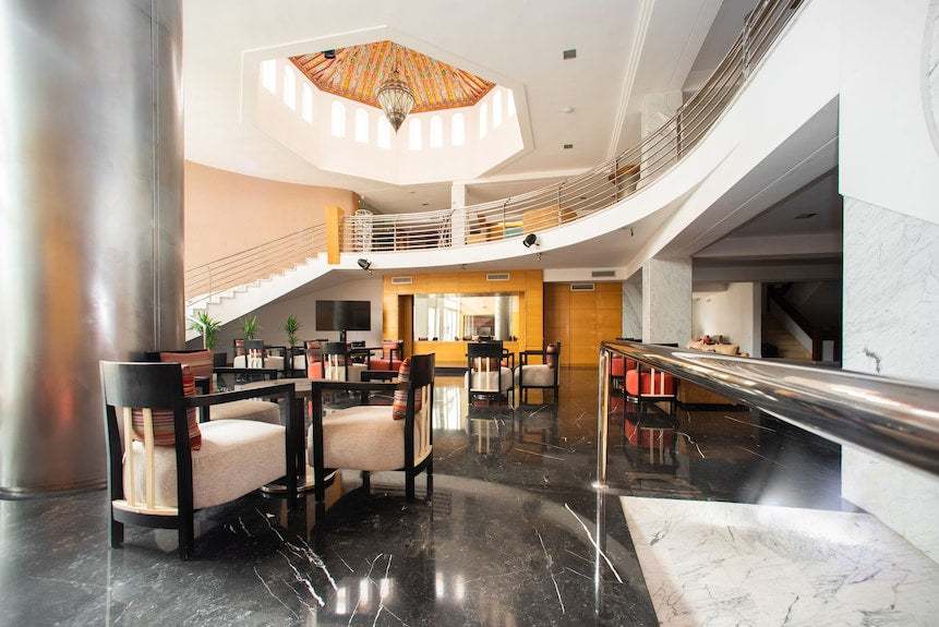 Lobby area of Timoulay Hotel & Spa Agadir featuring modern black and beige seating, polished black marble floor, and ornate ceiling detail