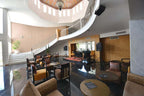 Lobby seating area with modern chairs, wooden tables, black marble floor, curved staircase, and colorful Moroccan-style ceiling at Timoulay Hotel & Spa Agadir