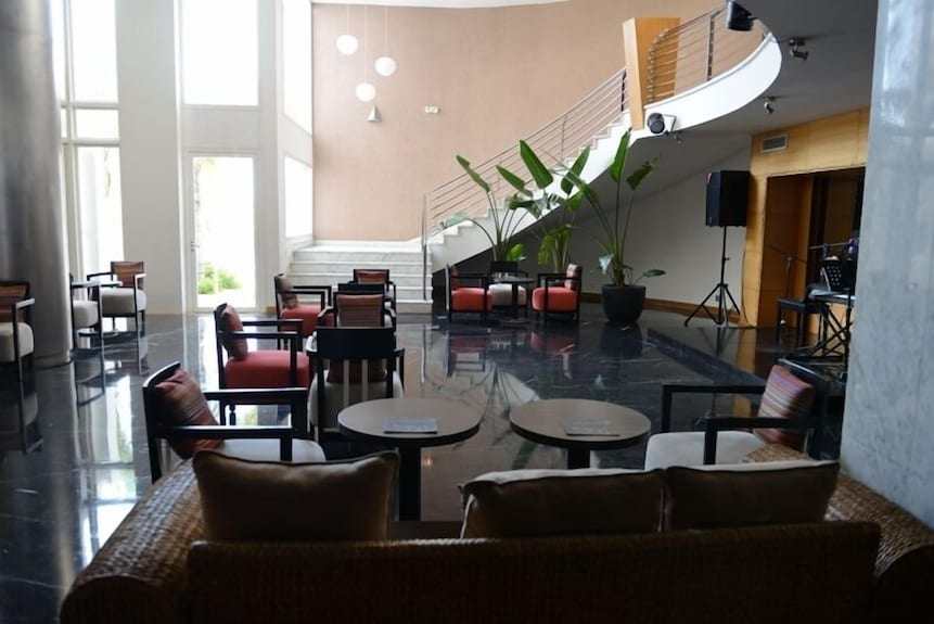 Spacious hotel lobby at Timoulay Hotel & Spa Agadir featuring modern furniture with red and brown cushions, black marble floor, and decorative plants