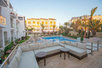 Timoulay Hotel & Spa Agadir outdoor swimming pool area with spacious beige cushioned seating, palm trees, and modern hotel buildings