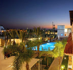 Swimming pool at Timoulay Hotel & Spa Agadir illuminated at dusk with surrounding palm trees and Moroccan-style buildings