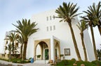 White modern Moroccan hotel building with arched entrance and palm trees at Timoulay Hotel & Spa Agadir
