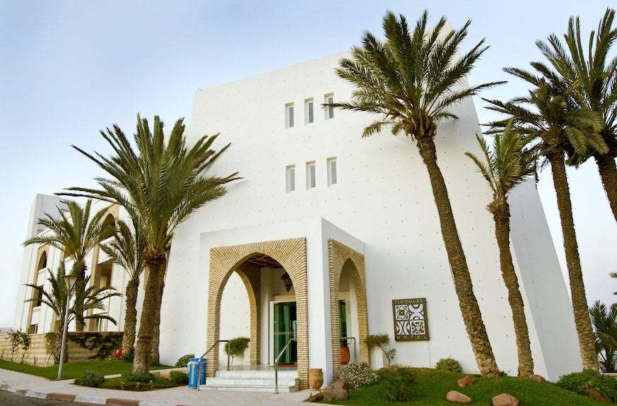 White modern Moroccan hotel building with arched entrance and palm trees at Timoulay Hotel & Spa Agadir