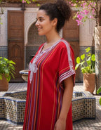 traditional Moroccan kaftan in vibrant red cotton with multicolored vertical stripes and white embroidered detailing on the front and sleeves