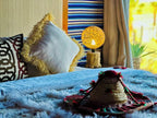 Yes We Camps Luxury Lodge & Spa bedroom with decorative pillows, textured bedding, woven lamp, and Moroccan hat on bed