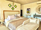 Yes We Camps Luxury Lodge & Spa cozy desert bedroom with beige and brown tones, patterned blanket, decorative pillows, and rustic wooden furniture