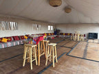 Interior of Yes We Camps Luxury Lodge & Spa featuring a spacious tent with woven floor mats, wooden stools, and colorful patterned cushions along low benches